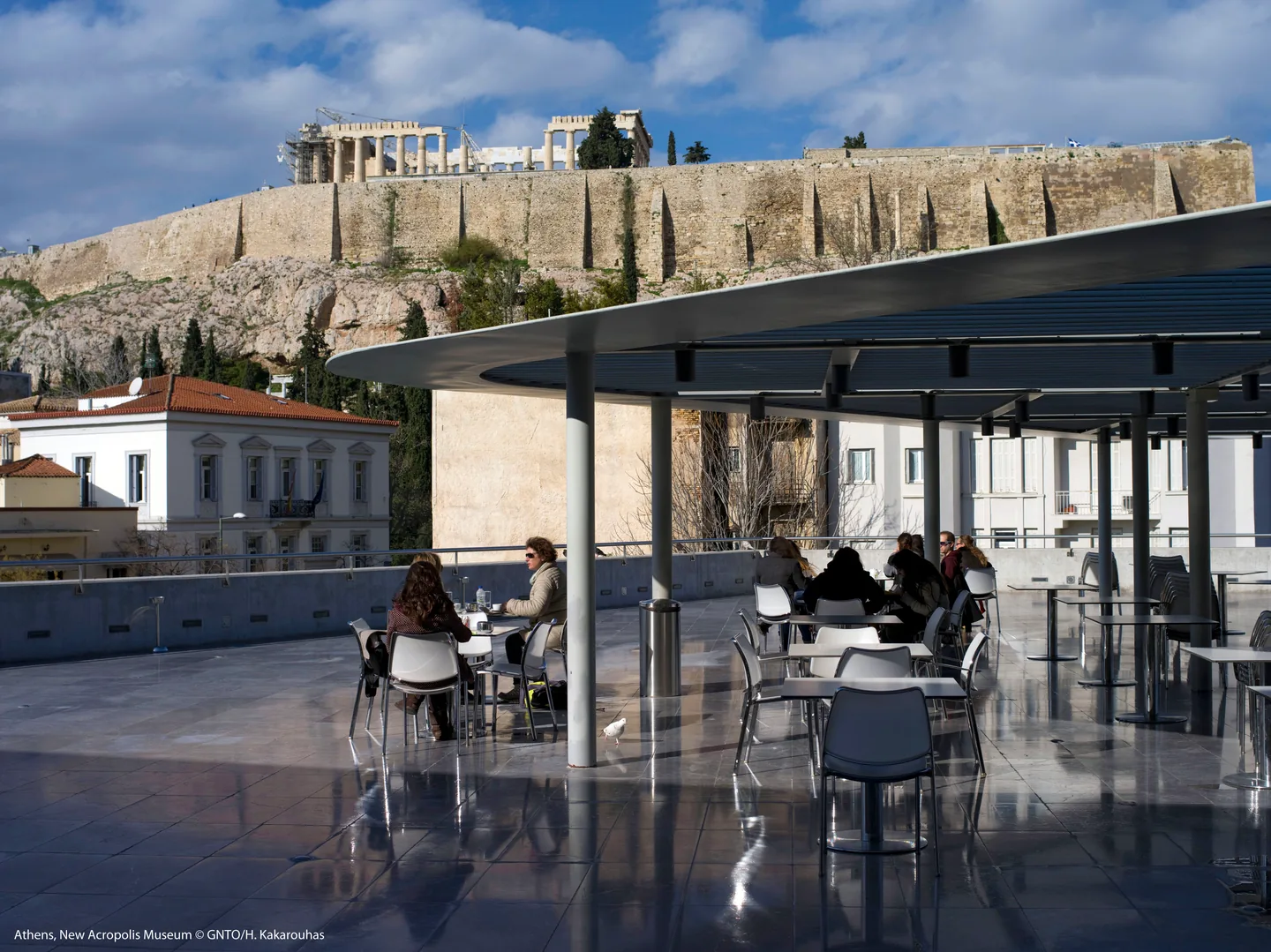 A pedestrian street with a café below the Acropolis