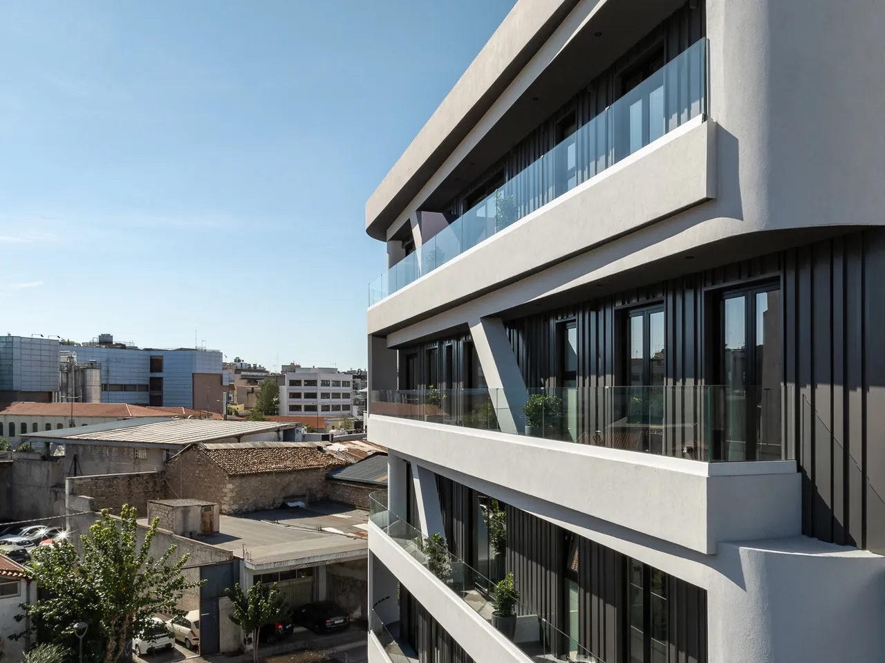 The exterior of FŌS by Naia — a pale, modern curved facade on a quiet Athenian street.