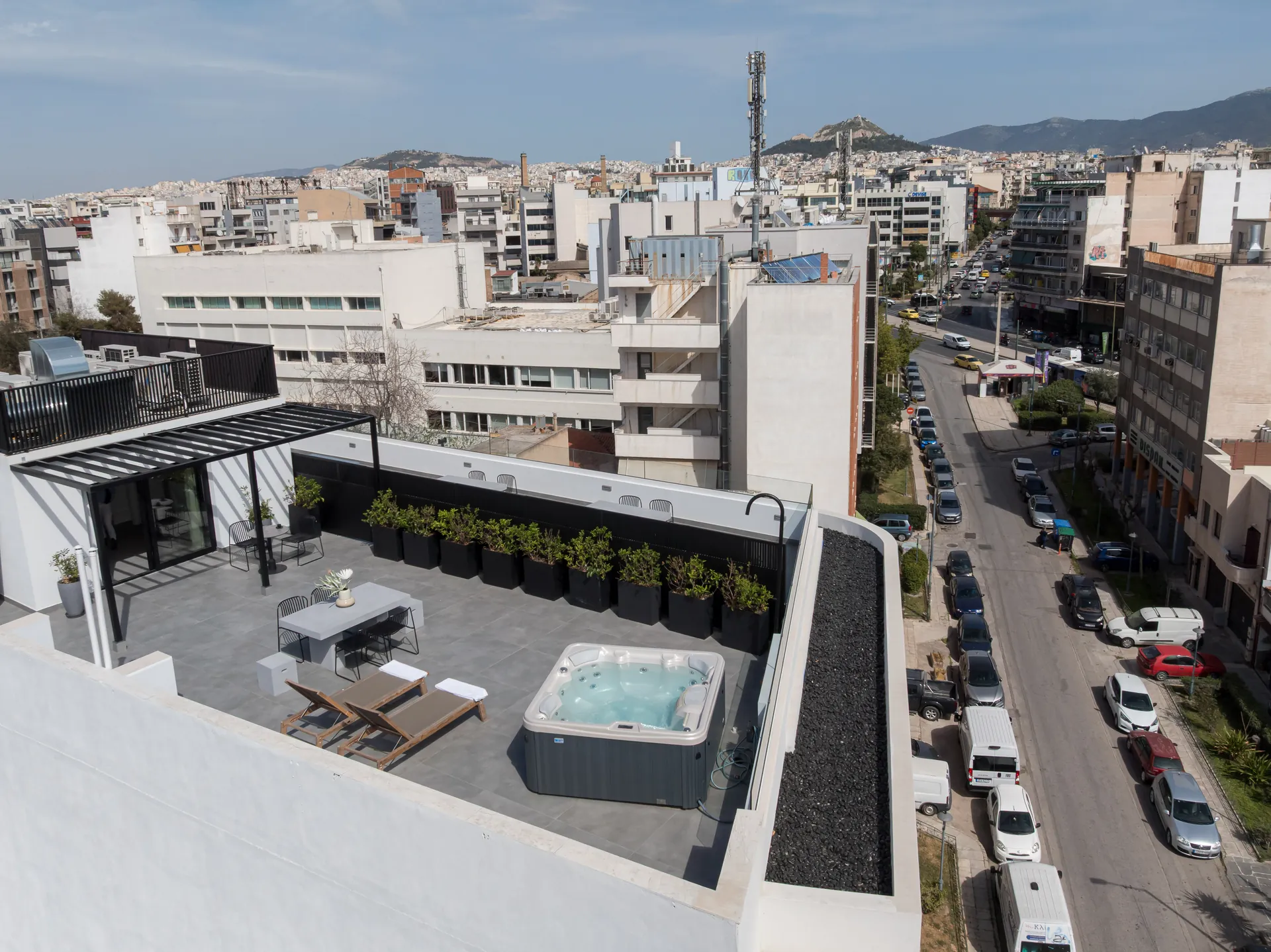 The FŌS rooftop in afternoon light, with the Lycabettus skyline behind it.